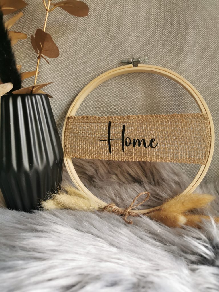 Stickring mit Schriftzug Home neben einer Vase